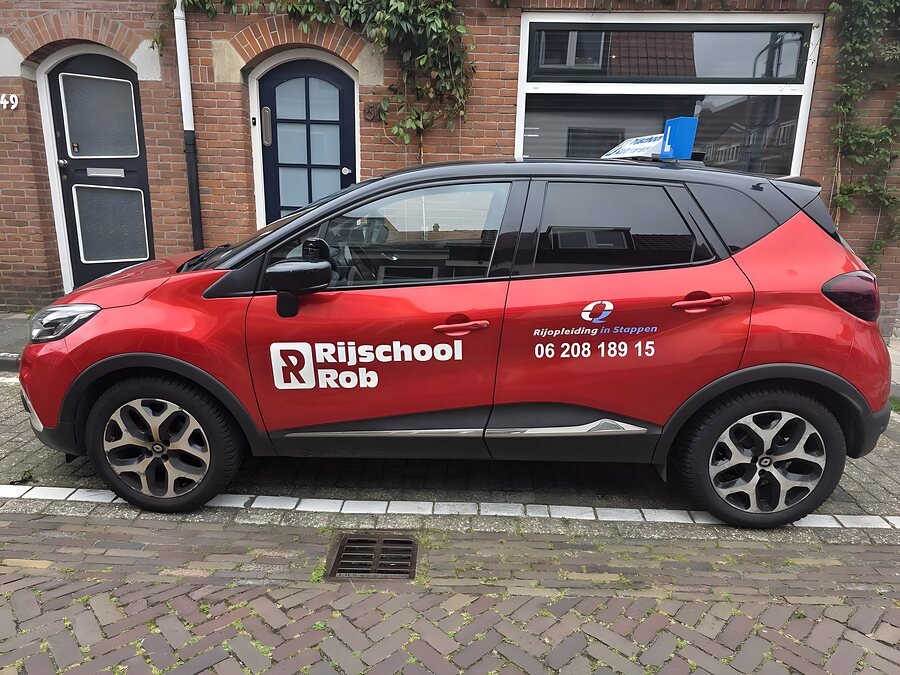 De rode Renault Captur schakelauto van Rijschool Rob in een Haarlemse straat